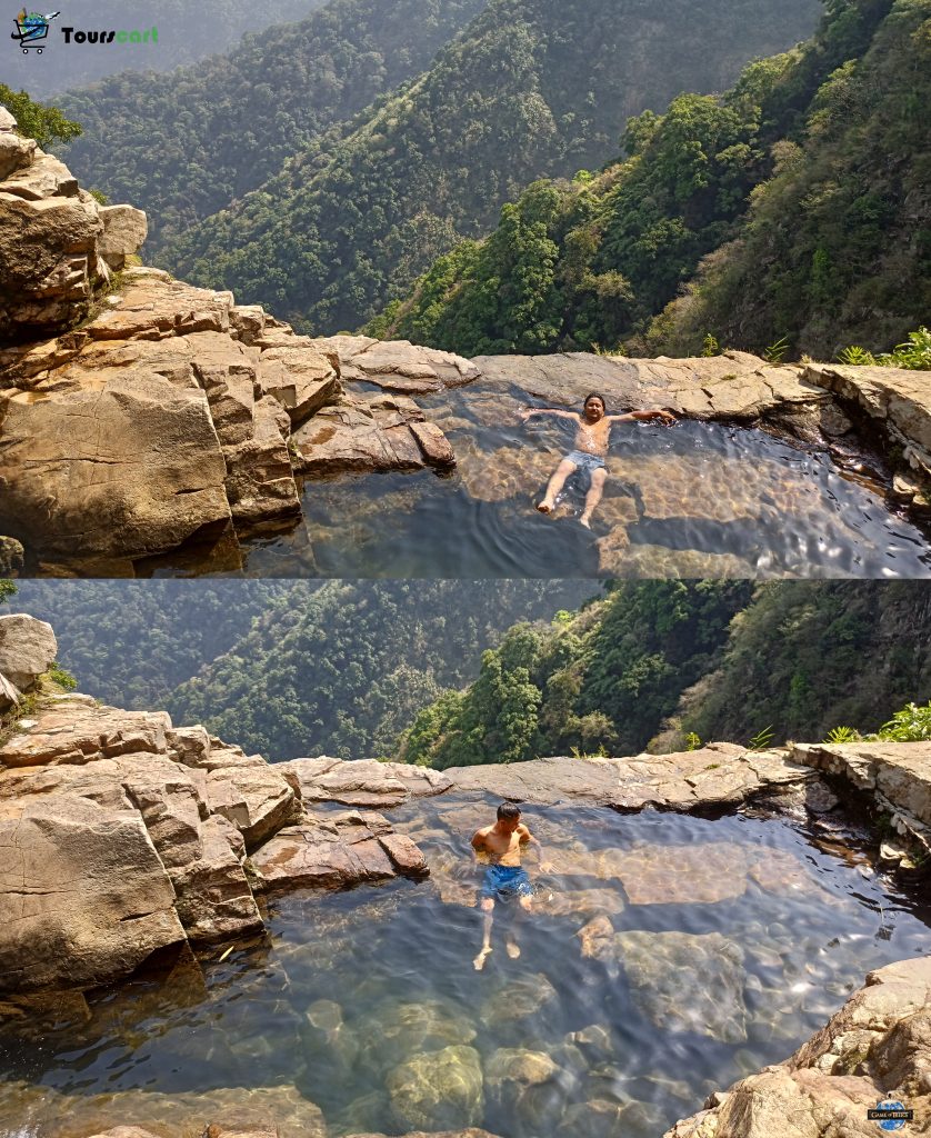 A serene natural swimming pool on a hillside in Nongnah Village, offering stunning views of the surrounding green valleys in Meghalaya.