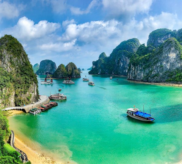 The stunning limestone karsts and emerald waters of Halong Bay, Vietnam, dotted with traditional boats, showcasing its serene natural beauty.